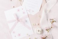 a super delicate wedding invitation suite with blush envelopes, neutral cherry blossom print invites and blush ribbon