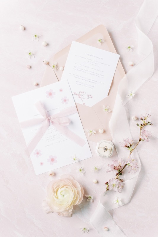 a super delicate wedding invitation suite with blush envelopes, neutral cherry blossom print invites and blush ribbon