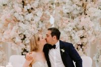 a super lush and gorgeous wedding reception space done with pink and white blooming cherry trees and blush roses is wow