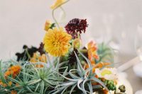 a textural wedding centerpiece of a gilded bowl, air plants, bold yellow and burgundy blooms is a great idea for a fall wedding