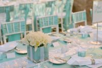 a tiffany blue and white table setting with white tulips in the box, signs, candles and white napkins