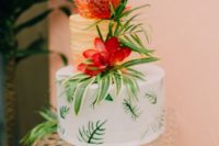 a tropical bridal shower cake with a gold tier, a white tier with greenery, blooms and greenery