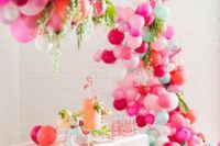 a tropical bridal shower dessert table accented with a super colorful balloon garland over it