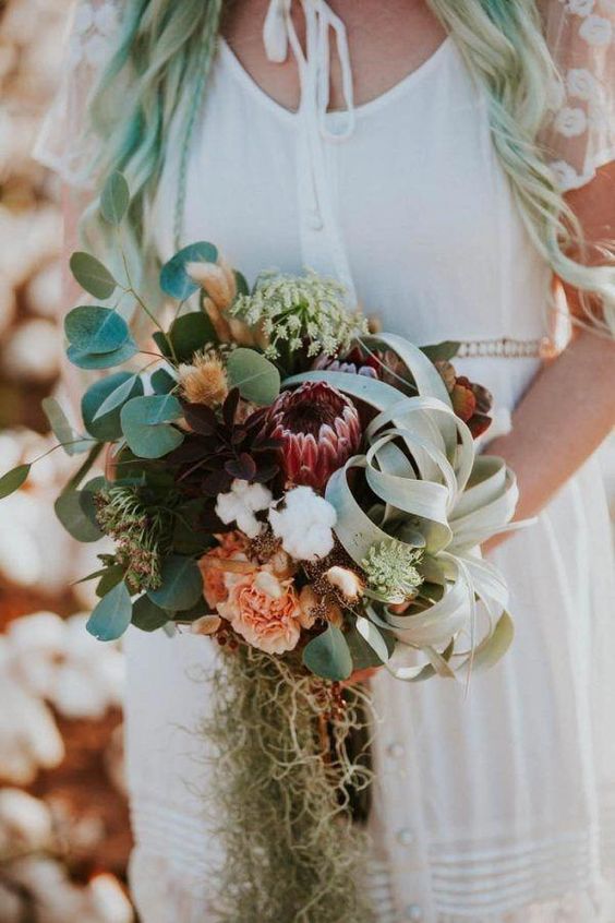 a unique wedding bouquet including a king protea, some peachy blooms, greeneyr, air plants and other stuff is a creative idea