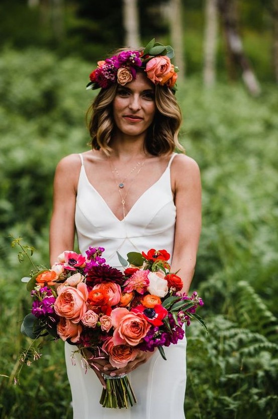 a vibrant wedding bouquet with pink, red, orange, burgundy and purple blooms including dahlias and anemones and greenery