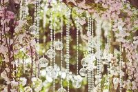a wedding arch with cherry blossom and hanging crystals is a gorgeous idea for outdoors