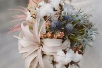 a wedding bouquet composed an an air plant, some cotton, dried blooms and blue thistles is a beautiful idea for a beach bride