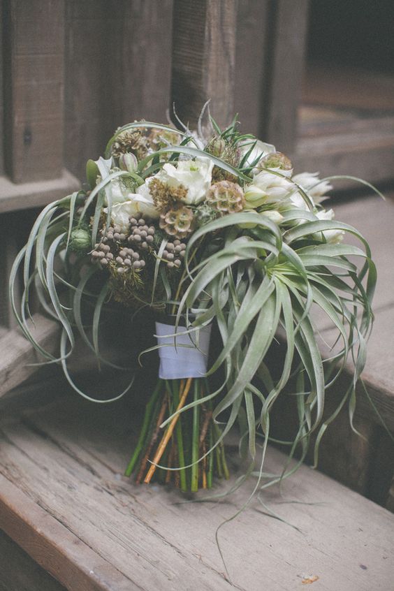 a wedding bouquet of greenery, air plants, berries and white blooms is a stylish solution for a modern wedding