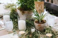 a wedding centerpiece of greenery, potted plants, candles is a stylish and budget-friendly idea, which is also sustainable