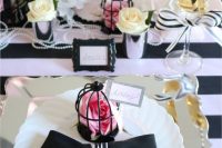 a whimsical Parisian-themed tablescape with a striped tablecloth, a black cage, neutral and pink blooms and some pearls is chic
