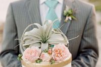 a white and gold wedding cake with pink blooms, berries and an air plant is a lovely idea for a boho wedding