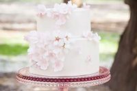 a white wedding cake decorated with blush cherry blossom looks simple, cute and very spring-like