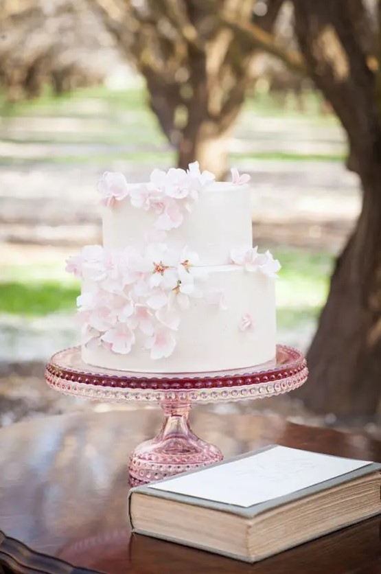 a white wedding cake decorated with blush cherry blossom looks simple, cute and very spring-like