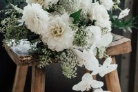 an all-white wedding bouquet of dahlias, roses, orchids, greenery and berries is a stylish idea for a modern bride