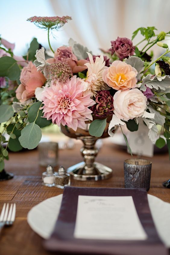 an elegant fall wedding centerpiece of blush and purpel dahlias, white and pink roses and some fillers and eucalyptus