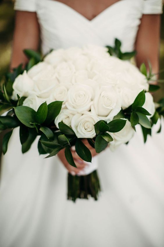 an elegant white rose wedding bouquet with greenery and a white ribbon wrap is a timeless idea