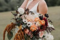 an eye-catchy and dimensional wedding bouquet of white anemones, yellow ranunculus and blush peony roses, dark blooms and greenery
