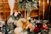 beautiful and lush fall rustic wedding decor with pumpkins, greenery, pink and red blooms including dahlias and candles in gold candleholders