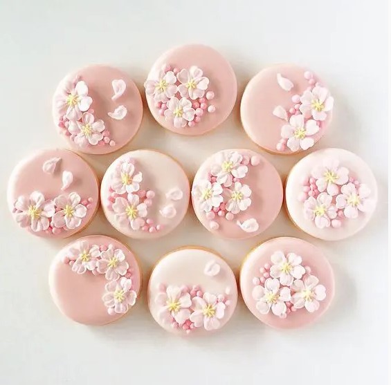 glazed pink wedding cookies decorated with pink cherry blossom and beads and petals will give a romantic feel to your wedding dessert table
