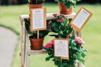 a ladder with bright potted flowers is a very creative rustic wedding seating chart idea