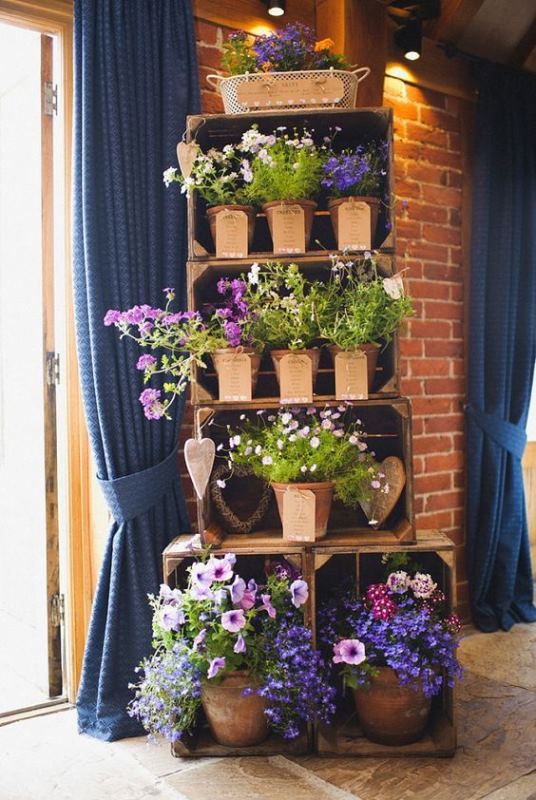 a creative seating chart of potted flowers in crates is a cool idea for a rustic wedding