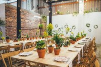 potted flowers and greenery lining up the wedding reception tables and greenery wreaths that refresh the space