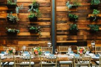 a stained wooden wall with planters attached to the wall and fresh greenery planted into them refresh the space