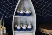 serve your cool cupcakes with anchor toppers in a cool boat and style your dessert table with net, candles and starfish