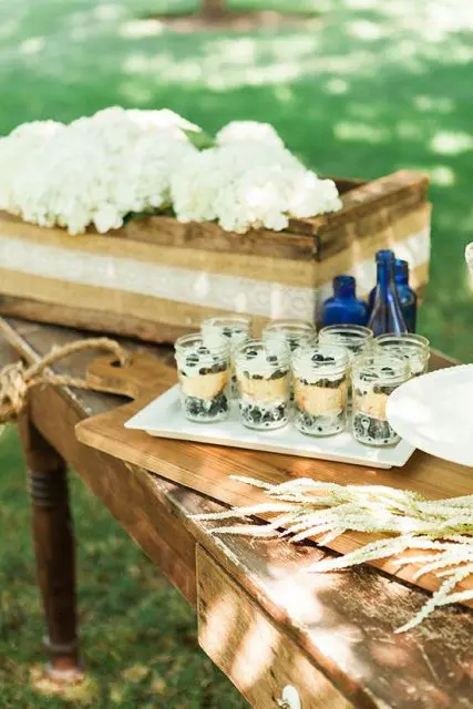 desserts displayed on a table with lace, wheat and a box with white hydrangeas for a rustic look