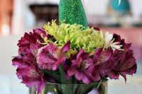 a fun mermaid bridal shower centerpiece of purple and green blooms and a sparkling mermaid tail is cool