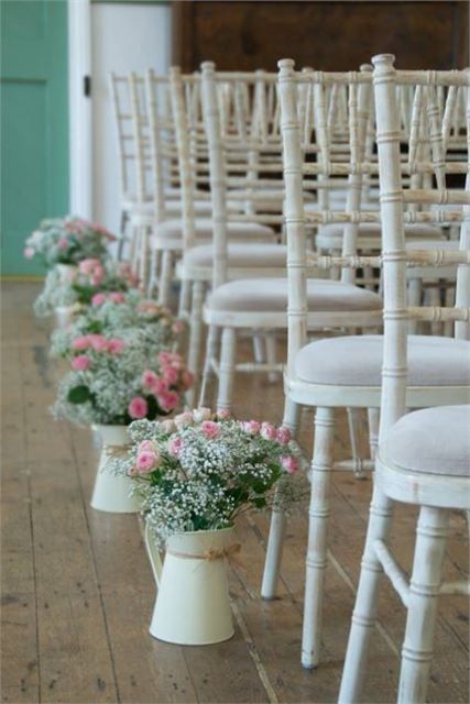 a beautiful vintage wedding aisle with white vintage chairs, white jugs lining up the aisle and holding pink roses and white baby's breath is an elegant and ethereal idea