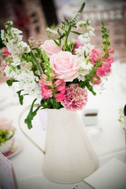 a pretty and lovely jug wedding centerpiece of a white porcelain jusg with blush, pink and white blooms and greenery is a lovely centerpiece idea for a rustic vintage wedding
