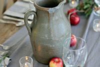 a rustic wedding tablescape with a grey table runner, candles, apples, greenery and a vintage porcelain jug is a chic idea