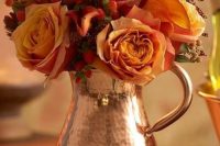 a beautiful hammered copper jug with orange roses, berries and a bit of greenery is a bright solution for a fall wedding