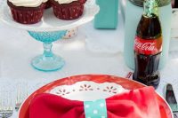 a blue, red and white bridal shower tablescape with bright plates, cupcakes and Coke in bottles