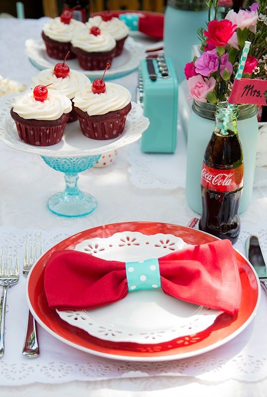 a blue, red and white bridal shower tablescape with bright plates, cupcakes and Coke in bottles