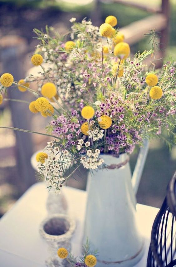 a boho wedding centerpiece of a blue metal jug, bold wildflowers and billy balls is a great idea for a bold wedding