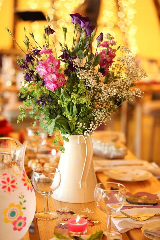 a bold boho wedding centerpiece of a white jug and bold blooms with greenery is a great idea for a summer wedding