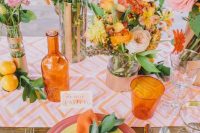 a bright retro wedding tablescape with a colorful printed table runner, colorful plates and napkins, bold blooms and greenery and copper vases