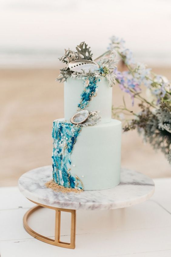 a catchy light green cake with gorgeous teal and navy detailing, seashells, corals and pearls is amazing for your mermaid bridal shower