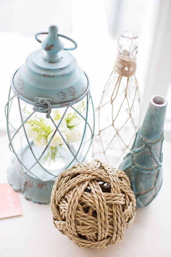 a cluster wedding centerpiece with a cage lantern, a bottle in fishing net anda rope ball is awesome for a mermaid bridal shower