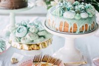 a coastal bridal shower dessert table with a naked cake with drip and mint meringues, mint buns and a chocolate cake with mint frosting on top