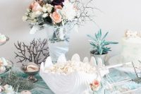 a lovely mermaid bridal shower dessert table with neutral and pastel blooms, popcorn in a seashell, macarons and various plants