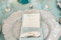 a lovely mermaid bridal shower tablescape with a mint blue tablecloth and napkins, a silver placemat, turquoise touches