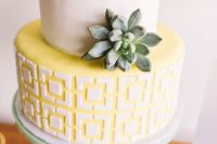 a mid-century inspired wedding cake with a white tier and a geometric yellow one plus a single succulent