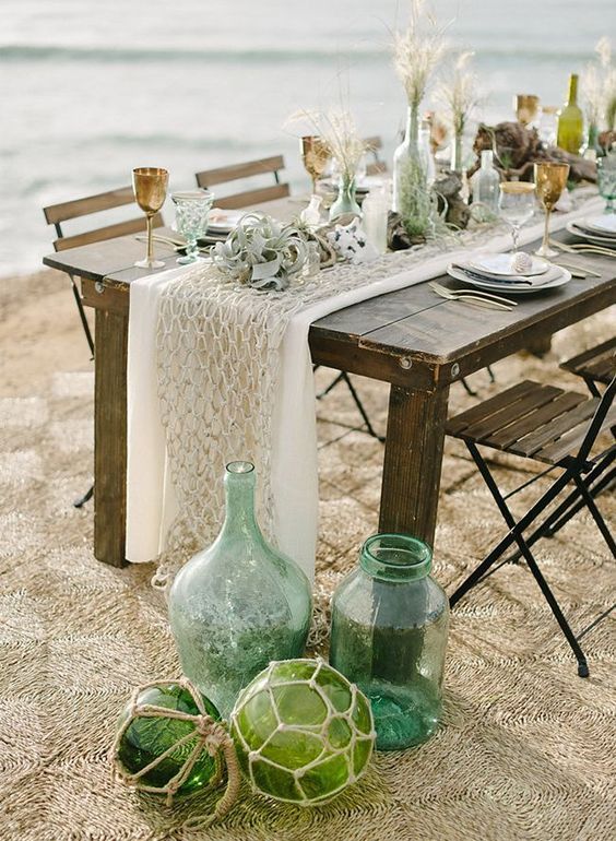 a neutral coastal tablescape with neutral runners, air plants and grasses with green bottles and glasses