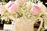a neutral spring or summer wedding centerpiece of a white floral jug with white and pink roses and baby’s breath