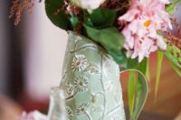 a pretty and chic wedding centerpiece of a green floral jug, greenery and pink blooms and berries is a cool idea for a rustic wedding
