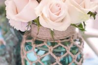 a pretty centerpiece of a jar in fishing net with pastel blooms canbe easily DIYed and it looks cool