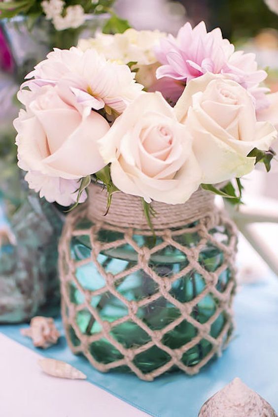 a pretty centerpiece of a jar in fishing net with pastel blooms canbe easily DIYed and it looks cool